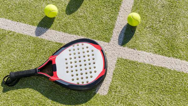 top view of a paddle tennis racket and balls on court of artificial grass, indoor sports concept and sporty lifestyle